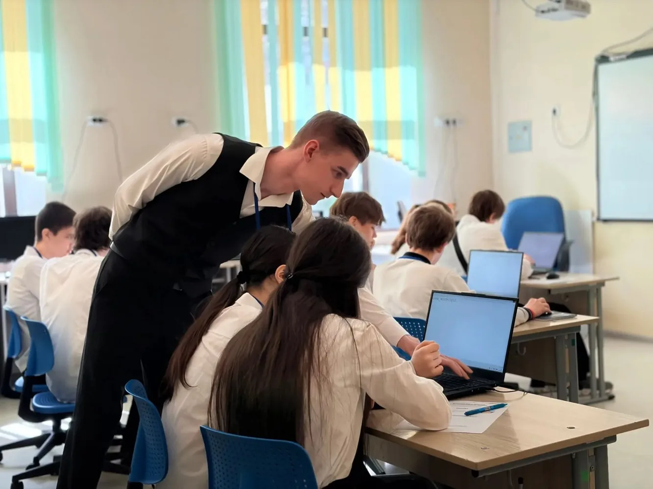 Андрей Куренков помогает ученикам на уроке информатики
